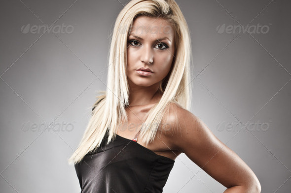 Full length portrait of a fashionable blond woman on gray background