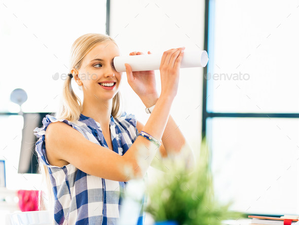 Young woman in casual clothes in an office with a paper tube